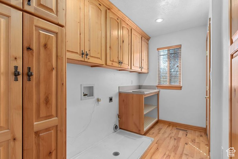 Laundry room with electric dryer hookup, light hardwood / wood-style floors, cabinets, and hookup for a washing machine