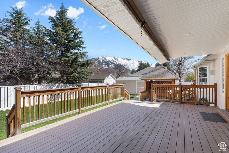 Wooden deck featuring a lawn and a mountain view