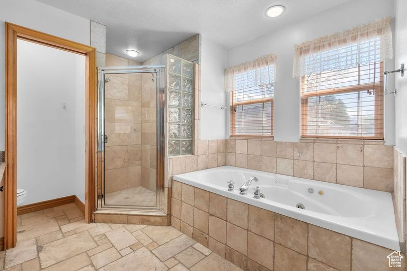 Bathroom featuring tile flooring, toilet, independent shower and bath, and a textured ceiling