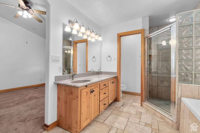 Full bathroom featuring tile flooring, ceiling fan, double sink, shower with separate bathtub, and oversized vanity