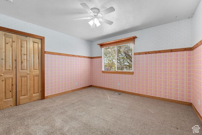 Unfurnished bedroom featuring ceiling fan, a closet, and carpet floors