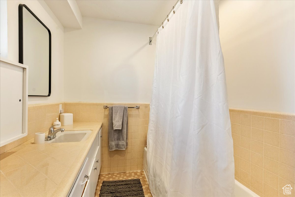 Bathroom with backsplash, tile walls, tile floors, and vanity with extensive cabinet space