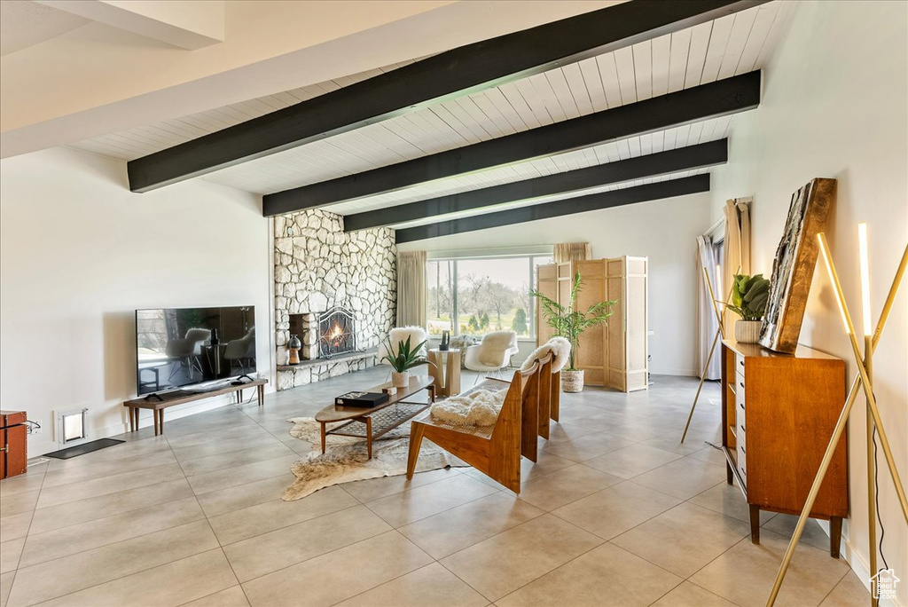 Tiled living room featuring vaulted ceiling with beams and a fireplace