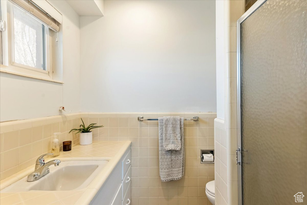 Bathroom with backsplash, tile walls, toilet, and vanity