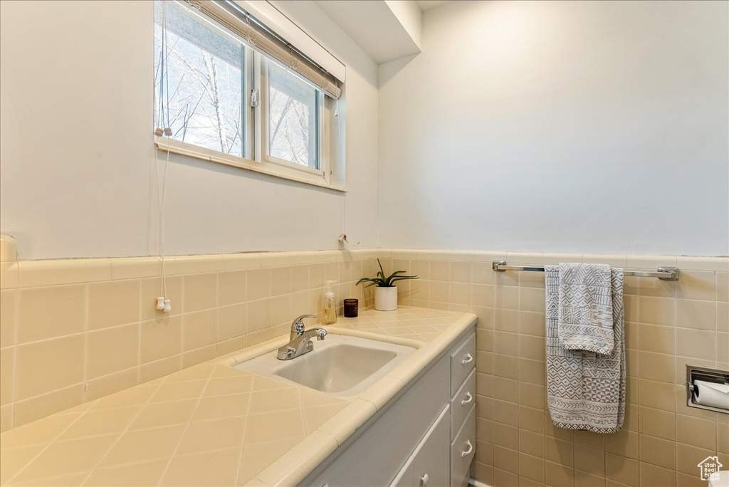 Bathroom featuring backsplash, tile walls, and vanity