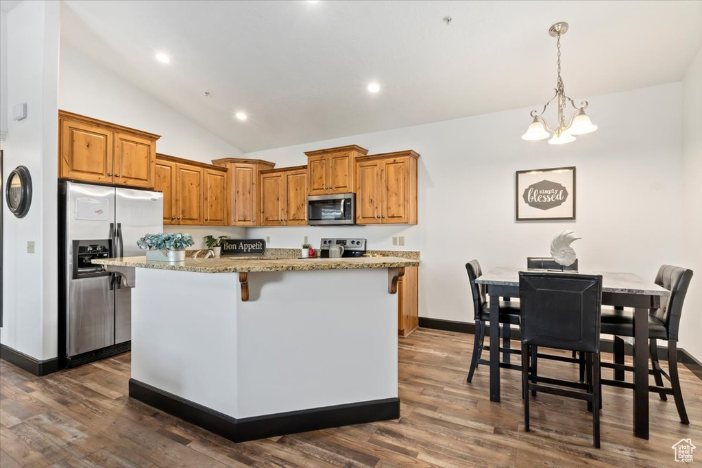 Kitchen with dark hardwood / wood-style floors, a kitchen island, stainless steel appliances, and decorative light fixtures