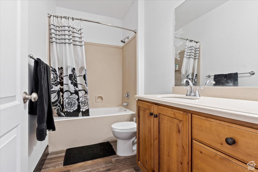 Full bathroom featuring toilet, hardwood / wood-style flooring, vanity, and shower / tub combo