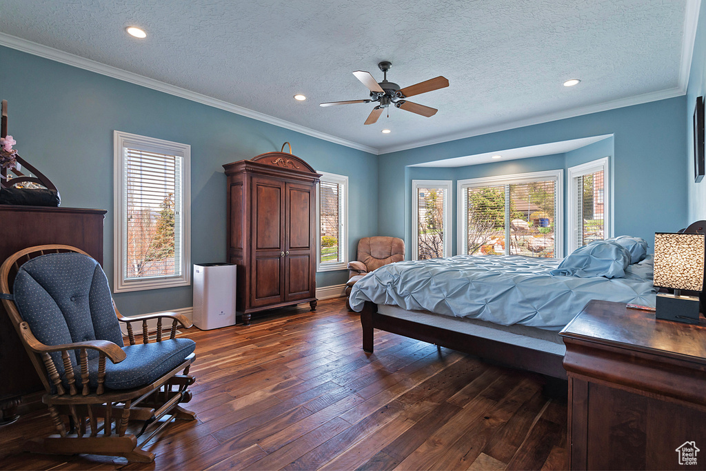 Bedroom featuring ceiling fan, crown molding, dark wood-type flooring, and a textured ceiling
