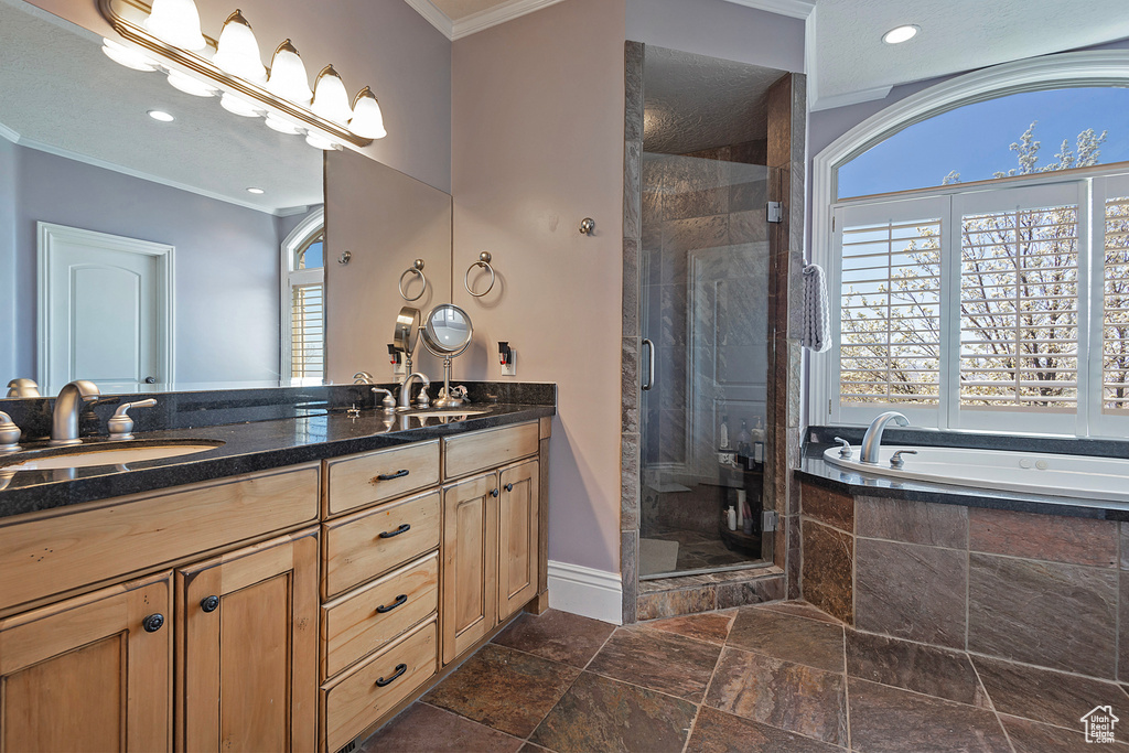Bathroom featuring tile flooring, ornamental molding, shower with separate bathtub, and dual vanity