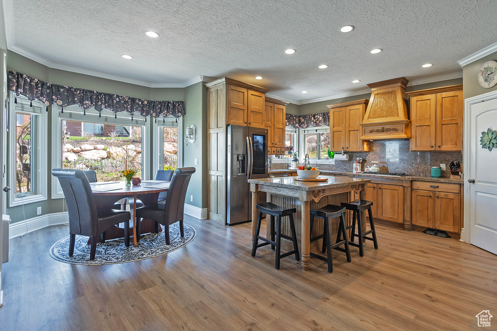 Kitchen featuring premium range hood, dark wood-type flooring, and a healthy amount of sunlight