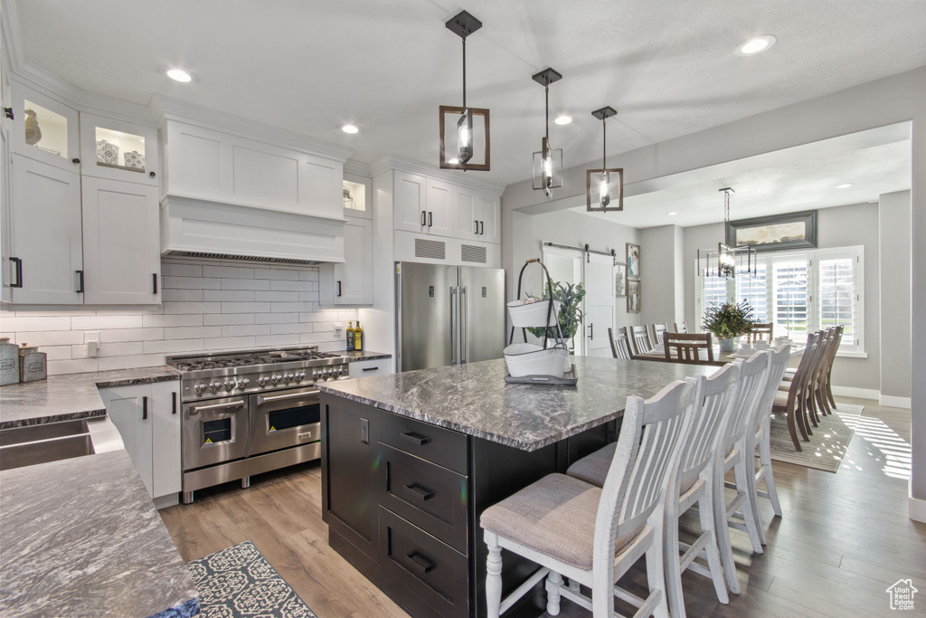 Kitchen with a center island, light wood-type flooring, high end appliances, and pendant lighting