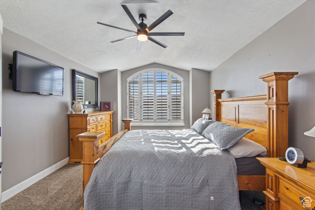 Bedroom with a textured ceiling, ceiling fan, dark colored carpet, and lofted ceiling