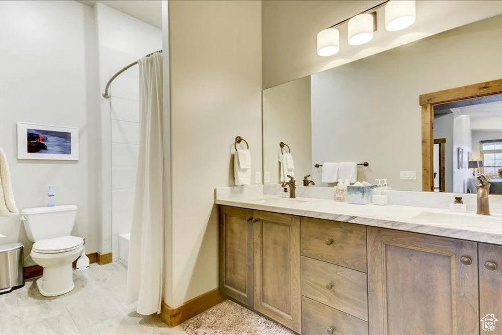 Full bathroom with shower / tub combo, tile floors, toilet, and double sink vanity