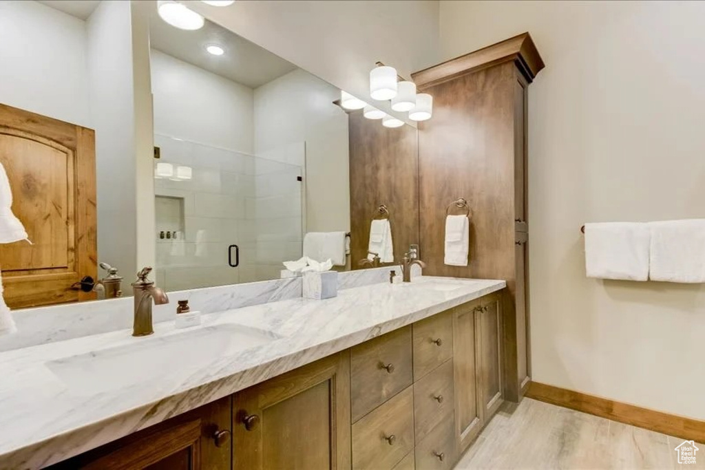 Bathroom featuring dual sinks, an enclosed shower, wood-type flooring, and large vanity