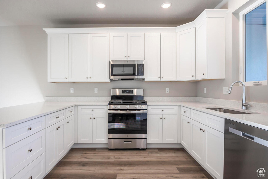 Kitchen featuring appliances with stainless steel finishes, sink, and white cabinets