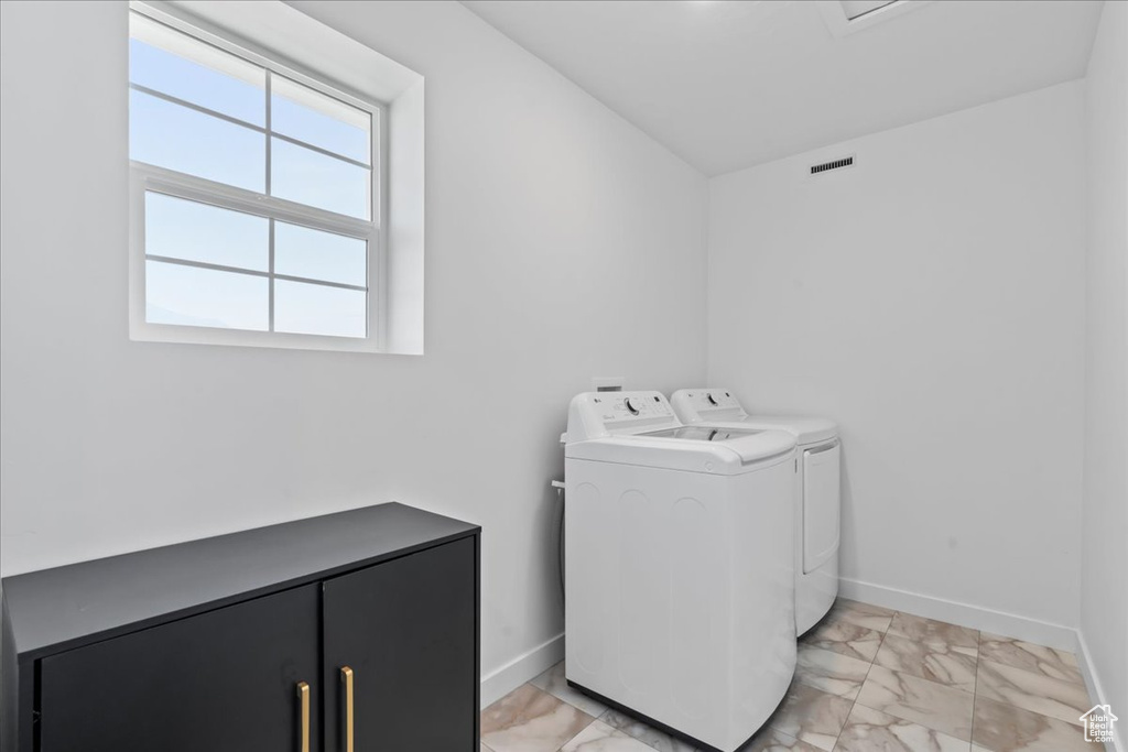Clothes washing area featuring cabinets, independent washer and dryer, and light tile flooring