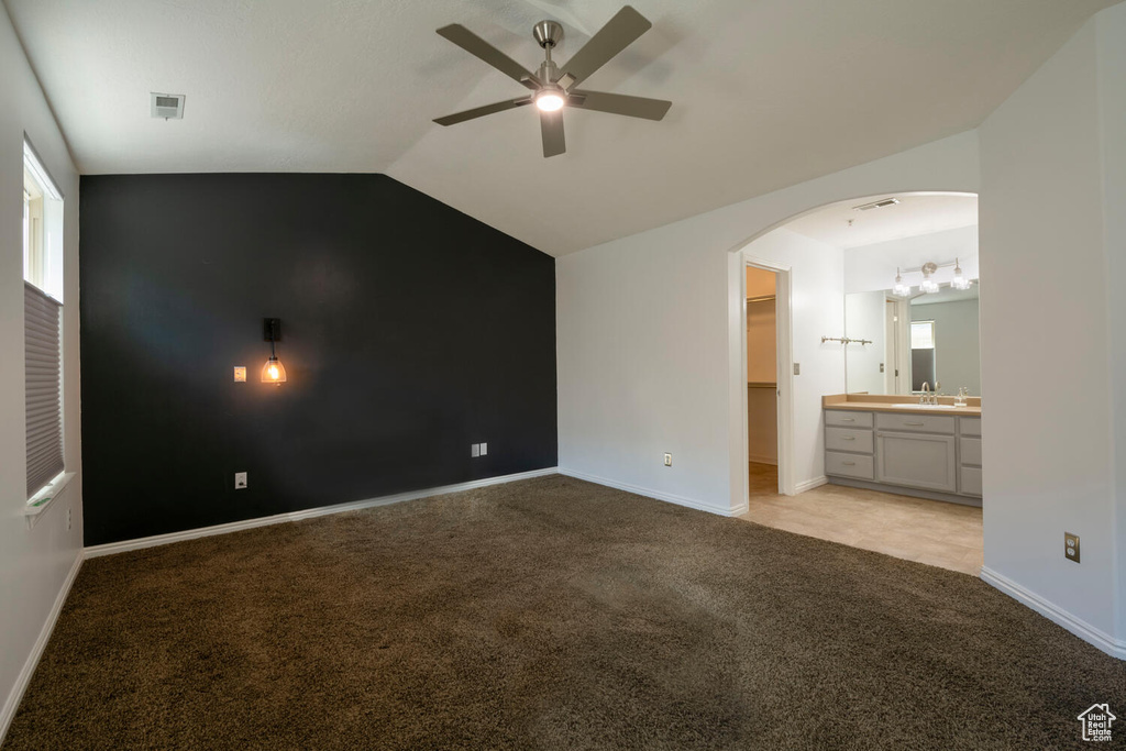 Empty room featuring sink, light colored carpet, ceiling fan, and vaulted ceiling