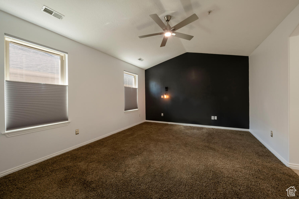 Carpeted spare room with ceiling fan and lofted ceiling
