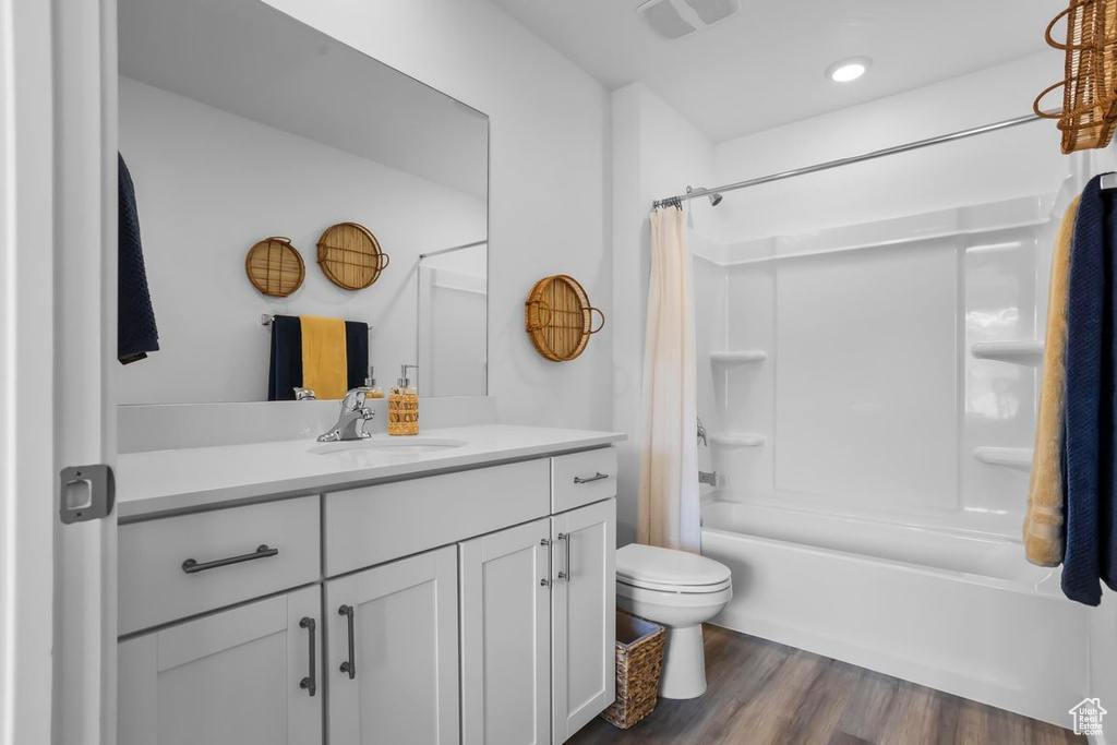 Full bathroom with vanity, toilet, hardwood / wood-style flooring, and shower / bath combo with shower curtain