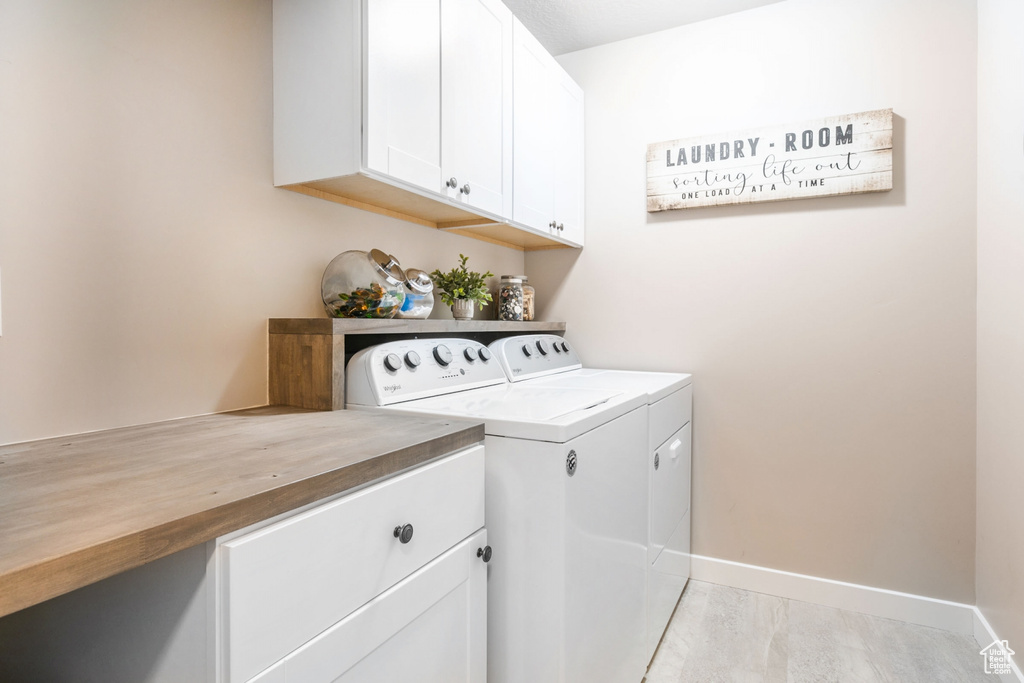 Laundry area featuring washer and clothes dryer, cabinets, and light tile flooring