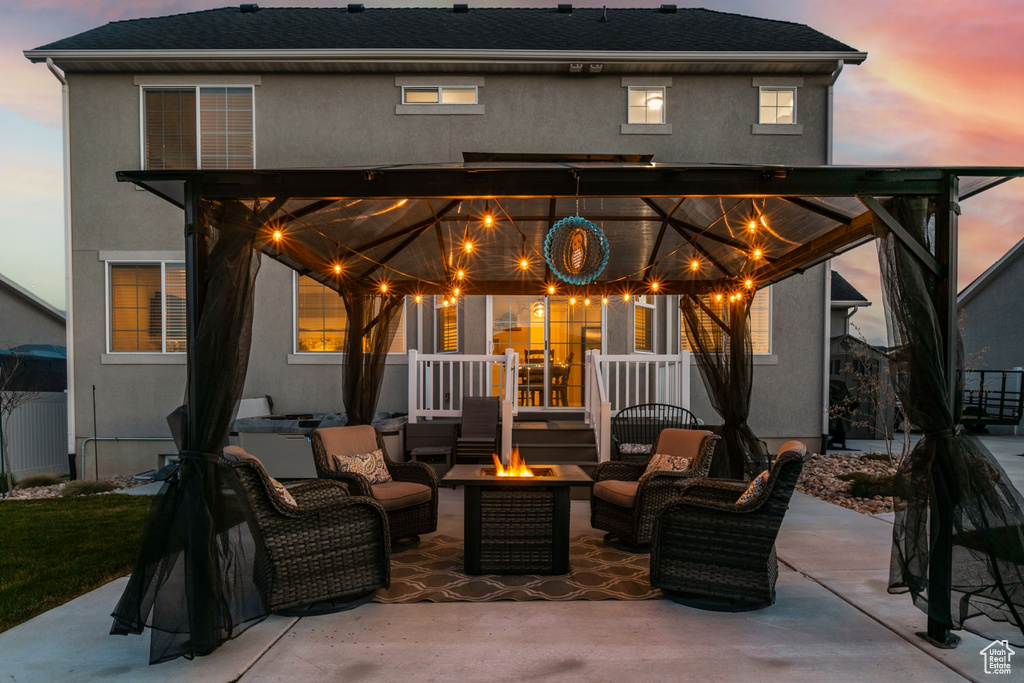 Back house at dusk with a patio area and an outdoor living space with a fire pit