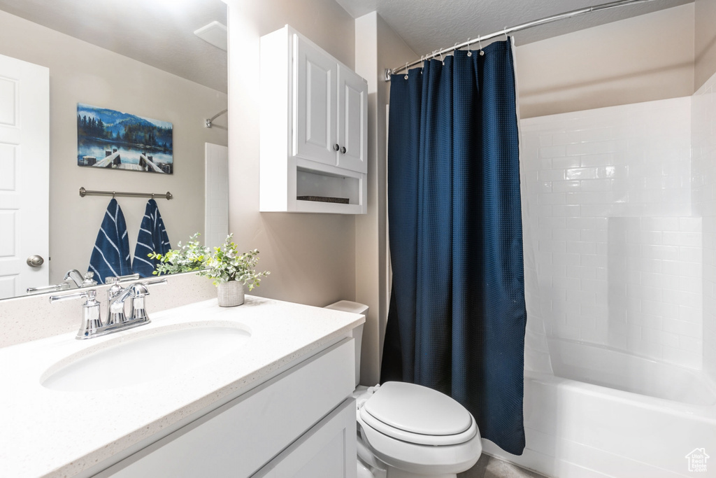 Full bathroom featuring shower / tub combo with curtain, a textured ceiling, toilet, and large vanity
