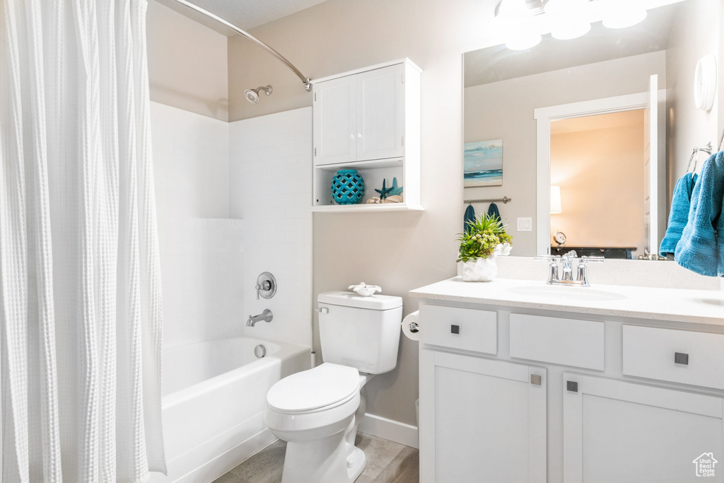 Full bathroom with toilet, large vanity, and shower / bath combo with shower curtain