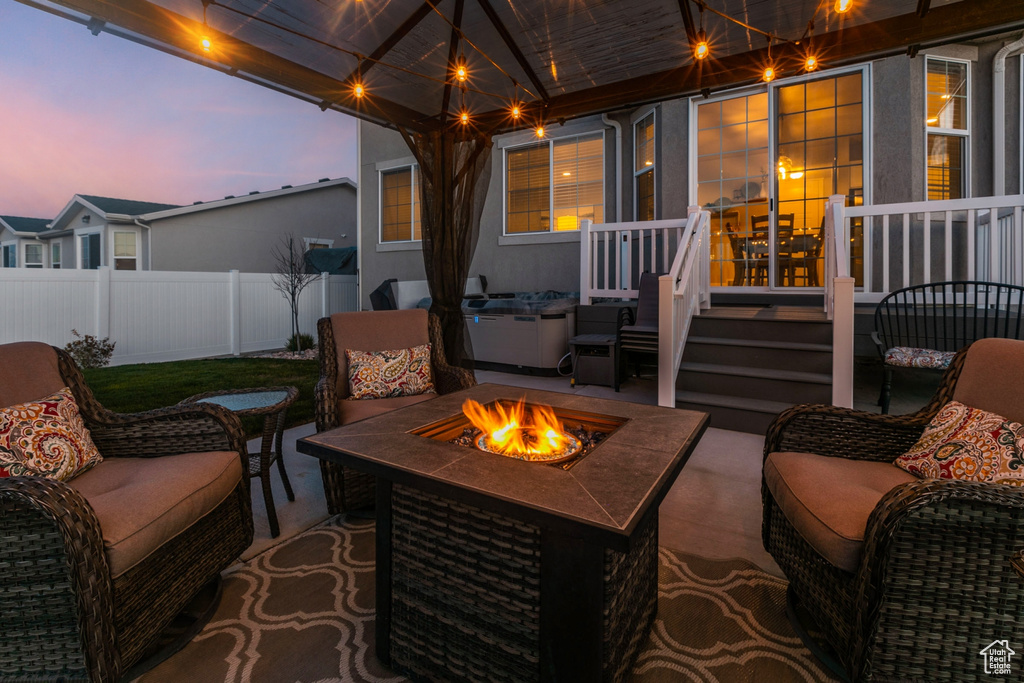 Patio terrace at dusk with a deck and an outdoor living space with a fire pit