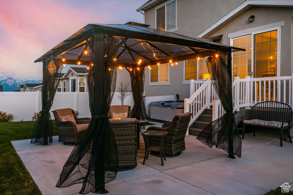 Patio terrace at dusk with an outdoor hangout area and a gazebo