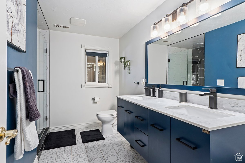Bathroom featuring tile flooring, toilet, double sink, and large vanity