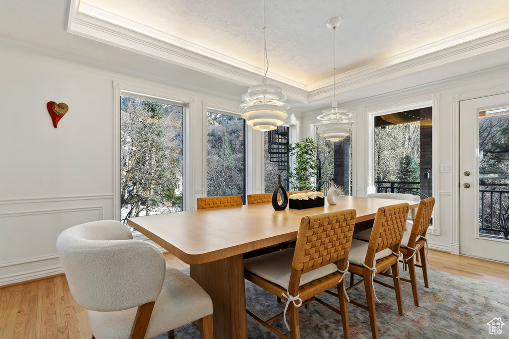 Dining room featuring light hardwood / wood-style flooring, a raised ceiling, and crown molding