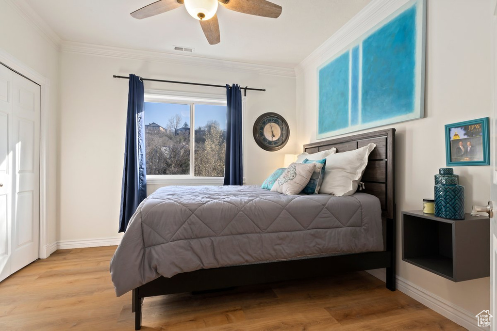 Bedroom featuring ornamental molding, light hardwood / wood-style floors, and ceiling fan