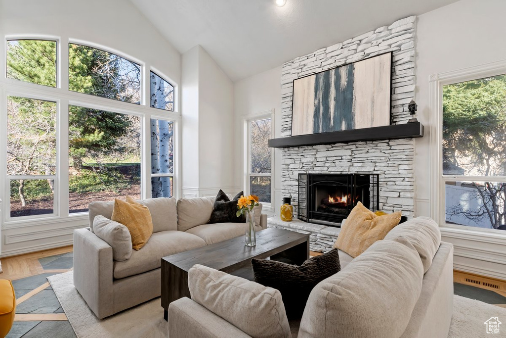 Living room featuring a fireplace, a wealth of natural light, vaulted ceiling, and light hardwood / wood-style floors