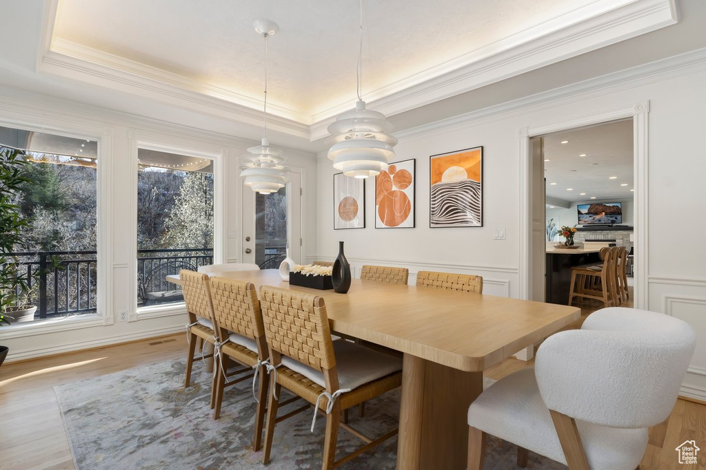 Dining space featuring crown molding, light hardwood / wood-style floors, and a raised ceiling