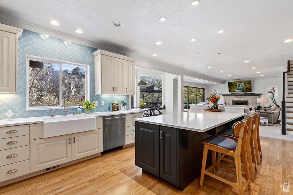 Kitchen featuring a kitchen island, light hardwood / wood-style flooring, dishwasher, tasteful backsplash, and sink