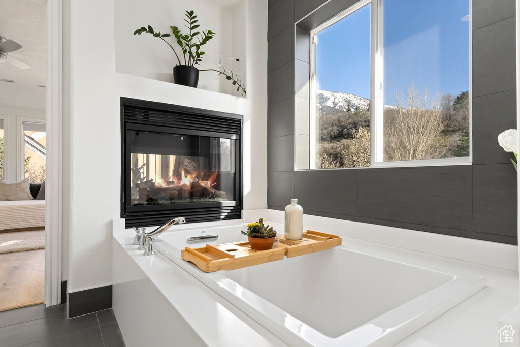 Details with dark tile flooring, a multi sided fireplace, and a bath to relax in