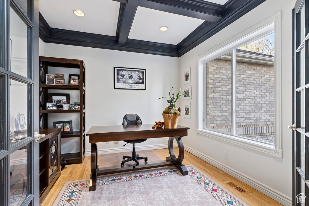 Office space featuring coffered ceiling, light hardwood / wood-style flooring, beam ceiling, and crown molding