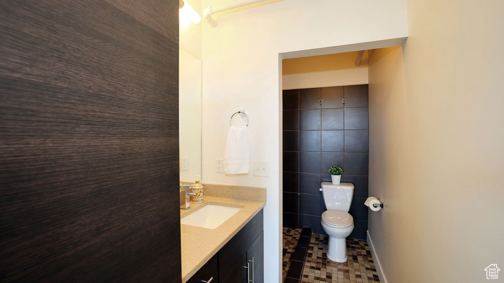 Bathroom featuring tile walls, toilet, tile floors, and vanity