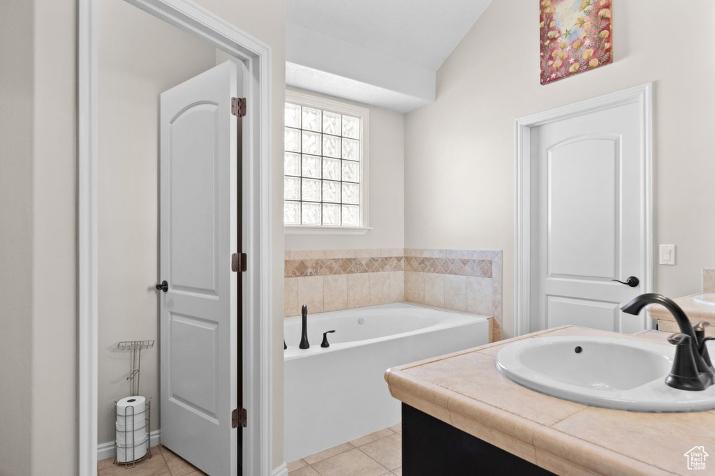 Bathroom featuring lofted ceiling, vanity, tile floors, and a bath