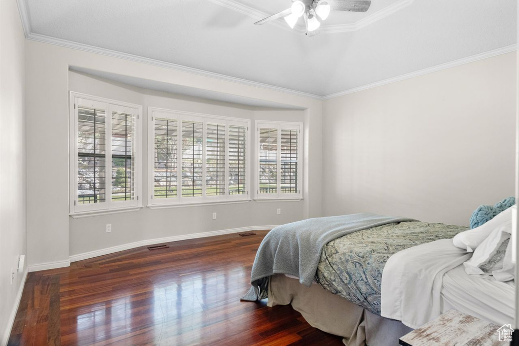 Bedroom with crown molding, dark hardwood / wood-style flooring, and ceiling fan