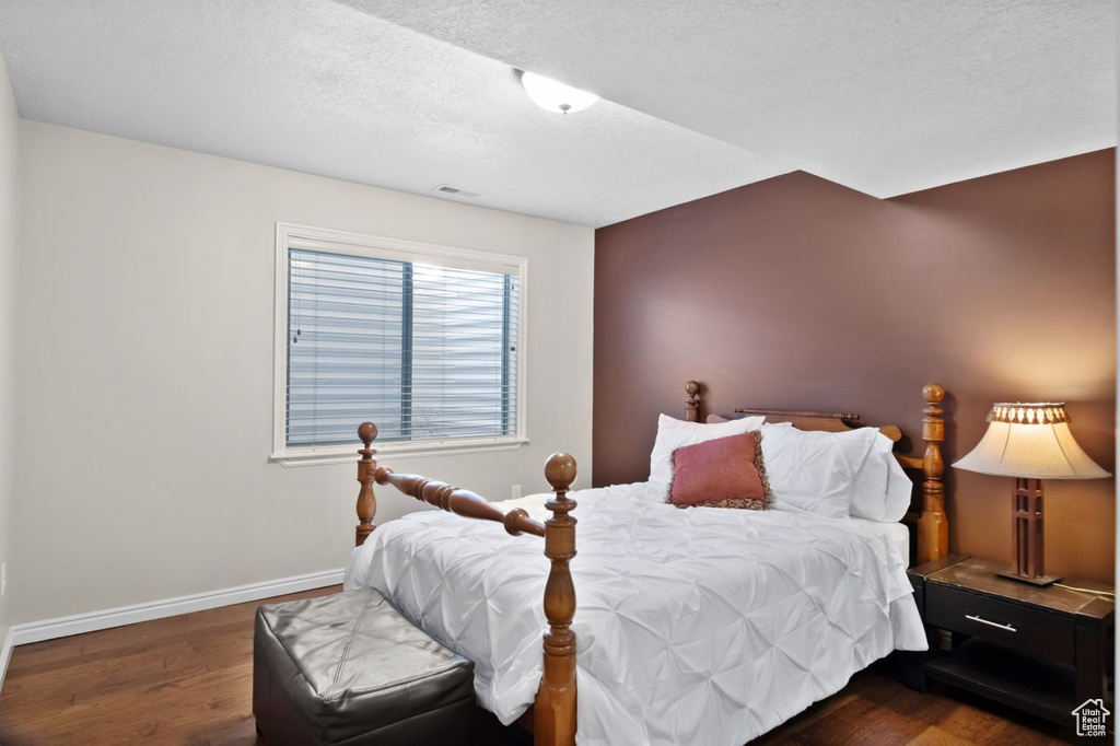 Bedroom with dark hardwood / wood-style floors and a textured ceiling