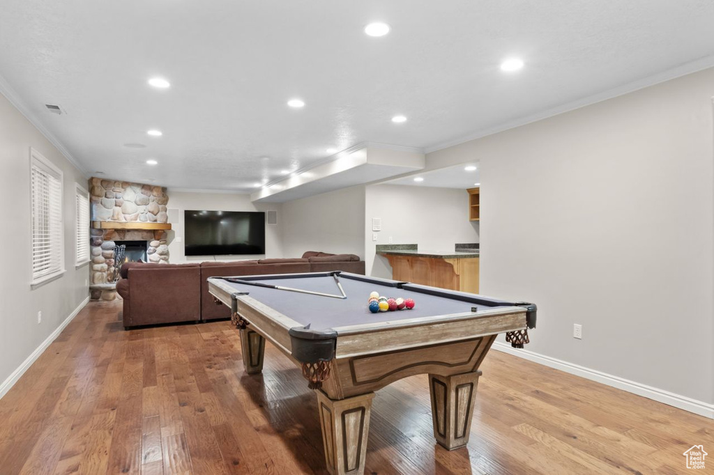 Recreation room featuring ornamental molding, light hardwood / wood-style floors, pool table, and a fireplace