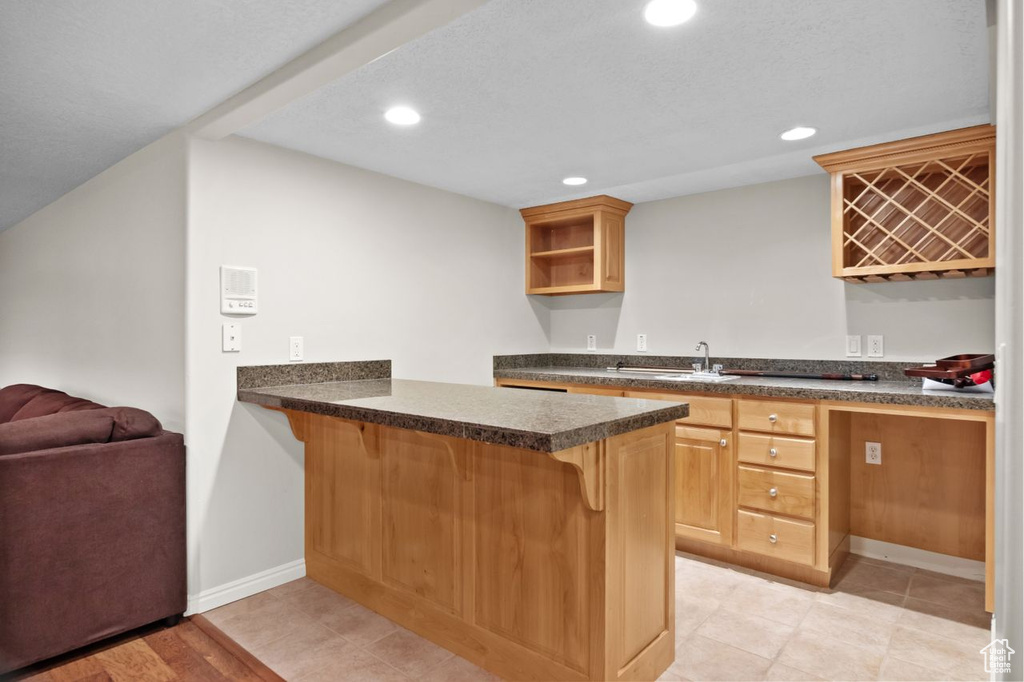 Kitchen with kitchen peninsula, a breakfast bar, sink, and light tile flooring