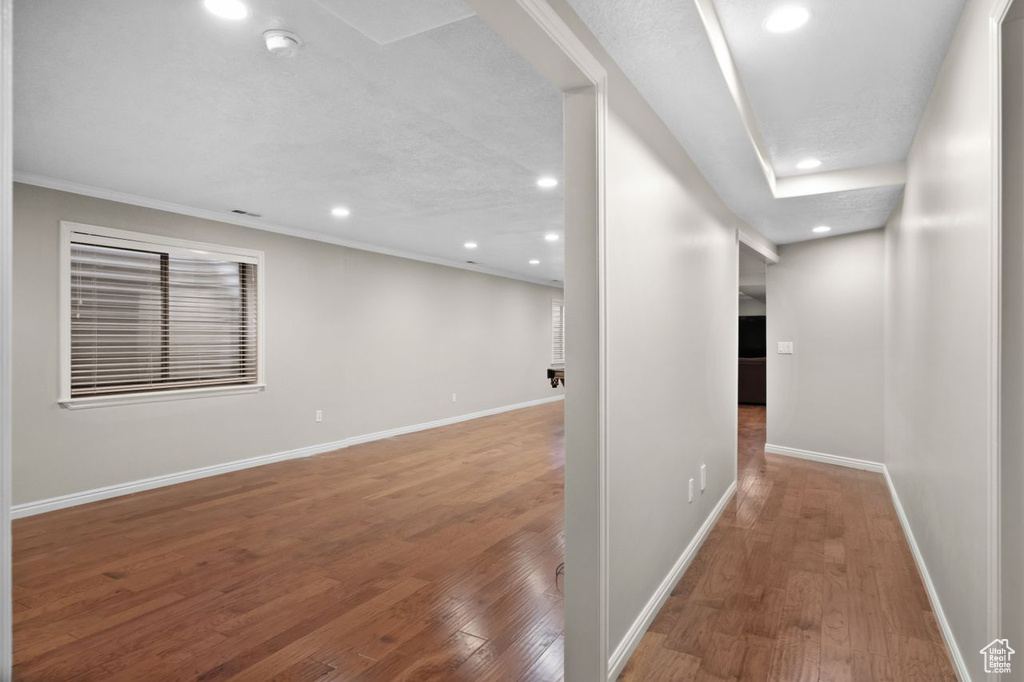 Corridor with ornamental molding and hardwood / wood-style floors