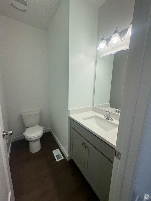 Bathroom with a textured ceiling, toilet, hardwood / wood-style floors, and vanity with extensive cabinet space