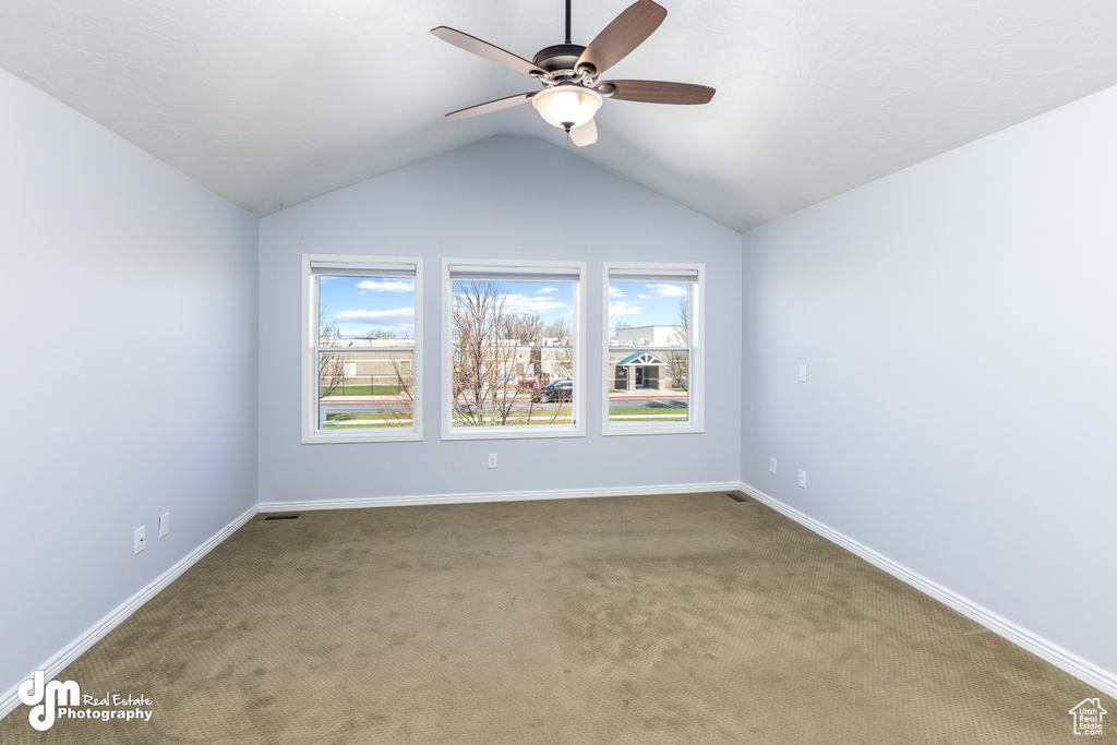 Unfurnished room featuring vaulted ceiling, ceiling fan, and dark colored carpet