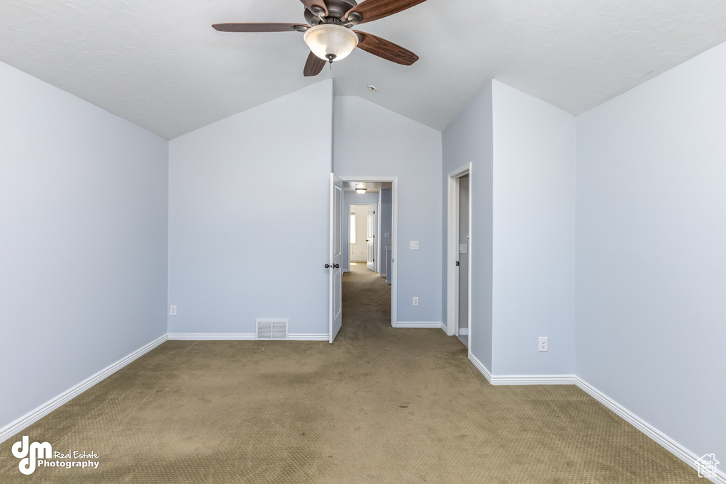 Empty room with light carpet, ceiling fan, and vaulted ceiling