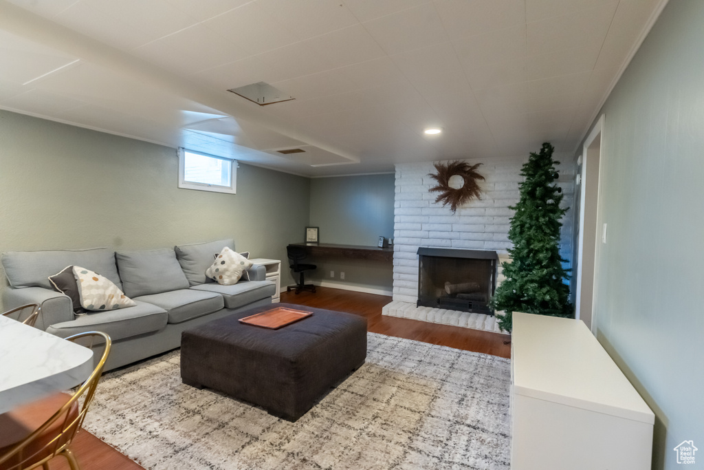 Living room with a fireplace, hardwood / wood-style flooring, and brick wall