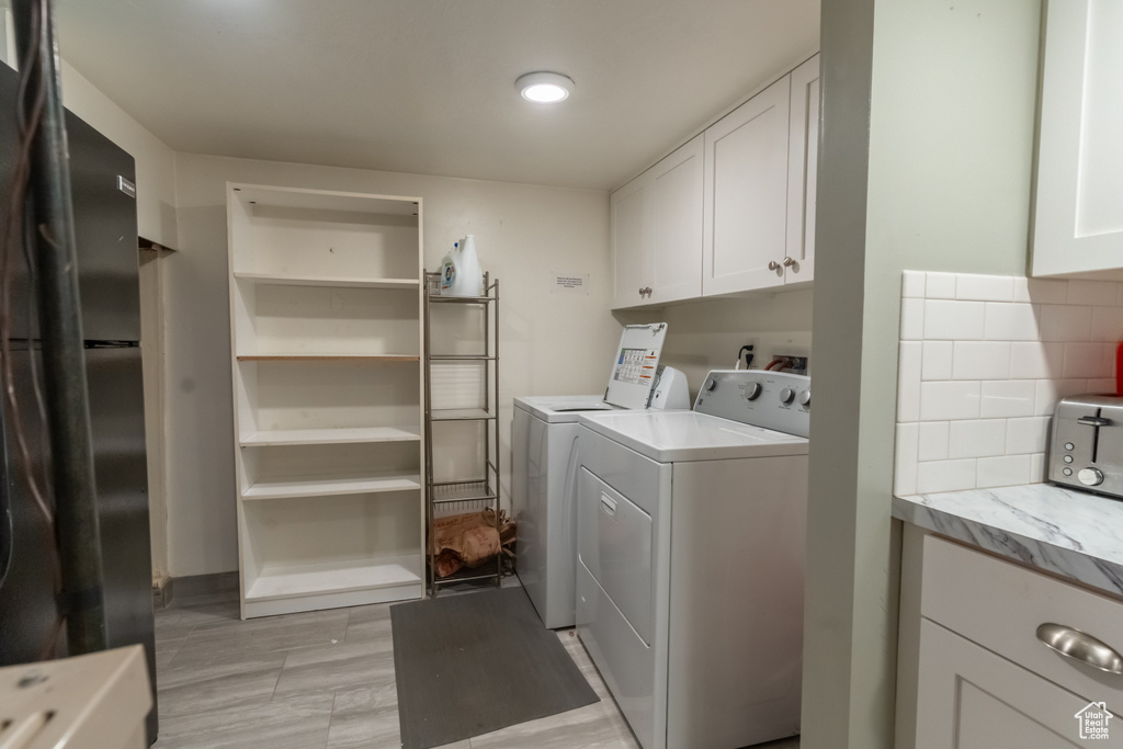 Laundry area featuring washer and clothes dryer, cabinets, and light wood-type flooring