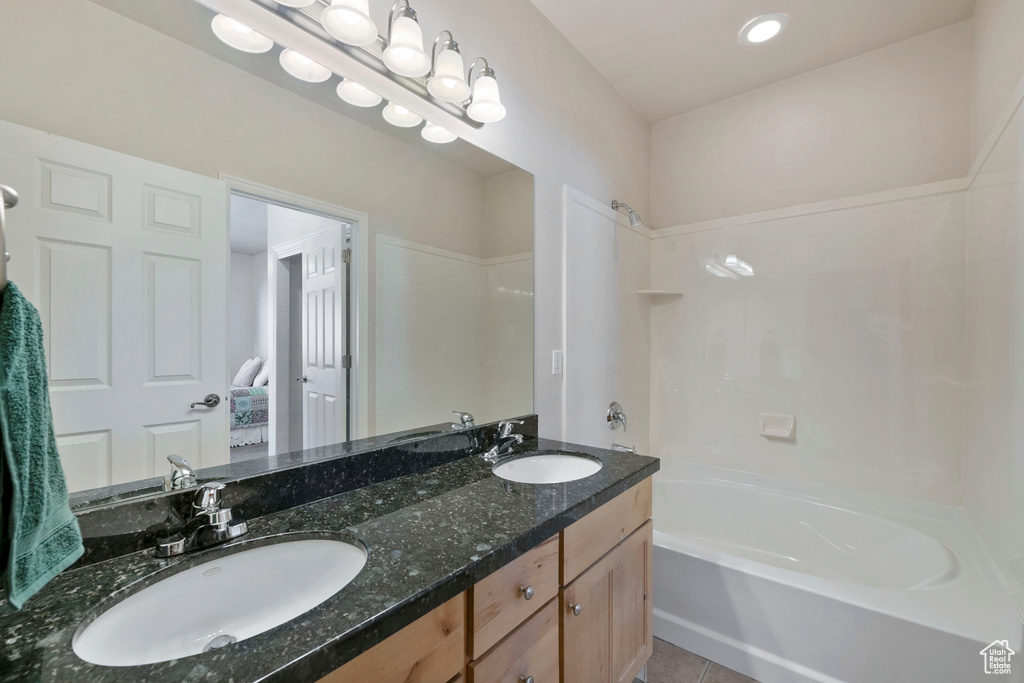 Bathroom featuring tile flooring, double sink, shower / tub combination, and vanity with extensive cabinet space